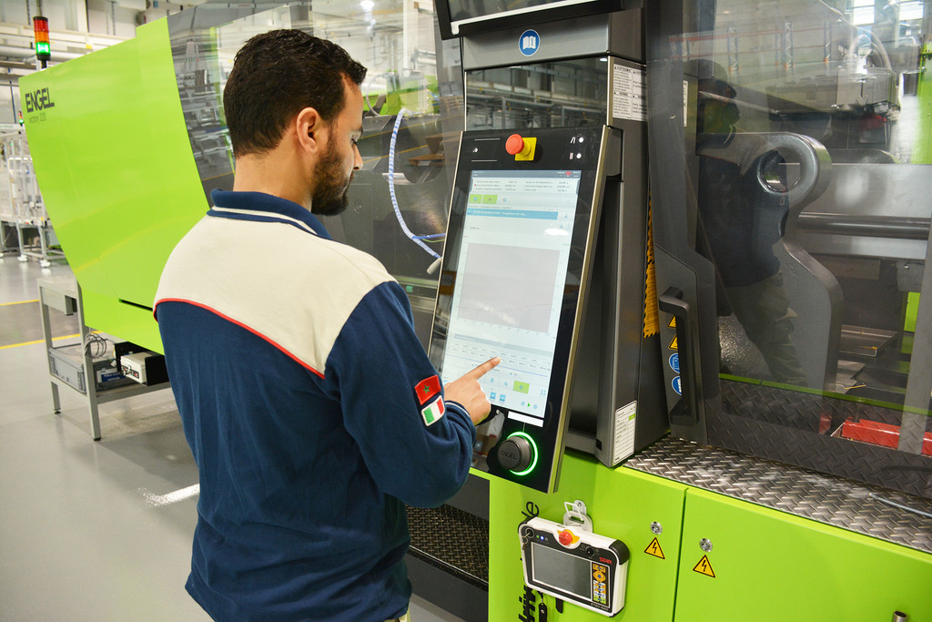 Opérateur au poste de contrôle d'une presse d'injection sur le site MTA